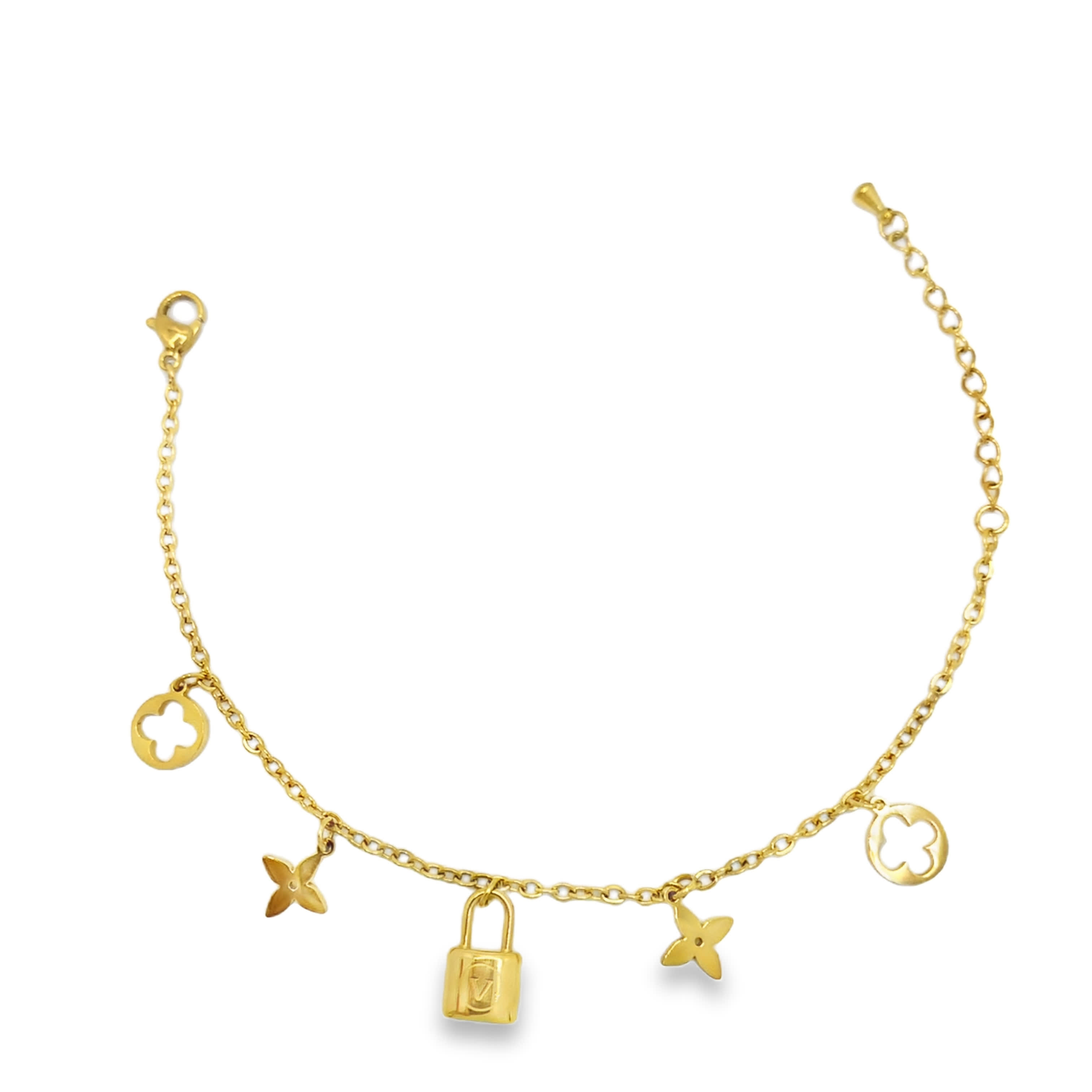 Złocona bransoletka z zawieszkami i kłódką oraz detalami w kształcie czwórliści